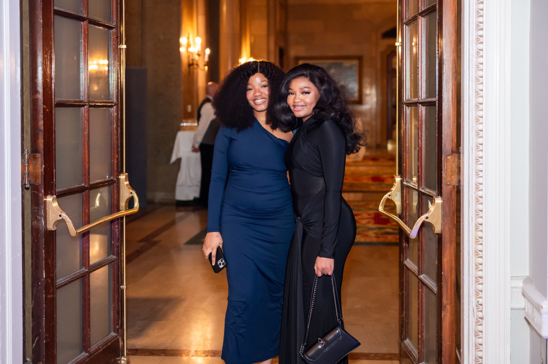 Two friends in navy and black evening gowns posing in the Fairmont doorway