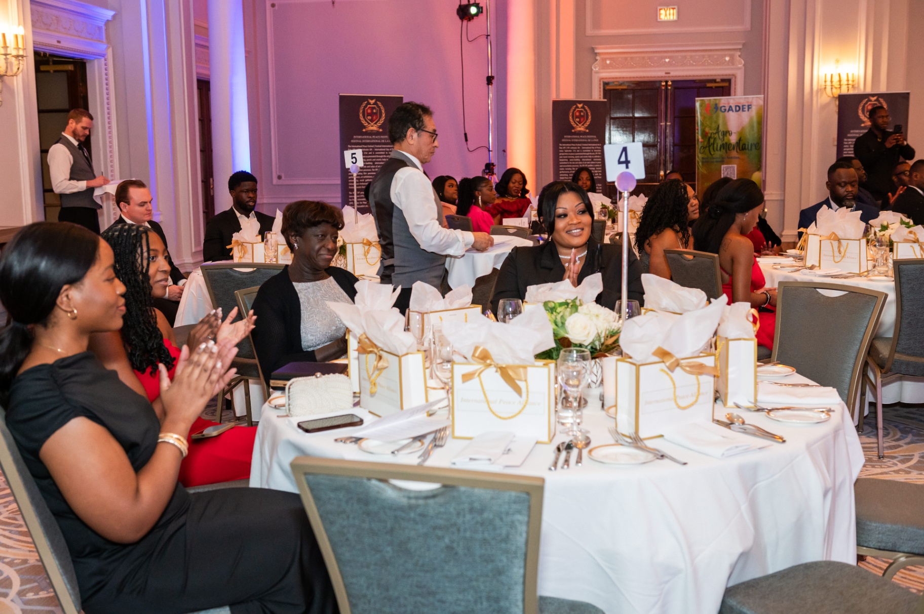 Guests applauding at a table set with International Peace Alliance gift bags