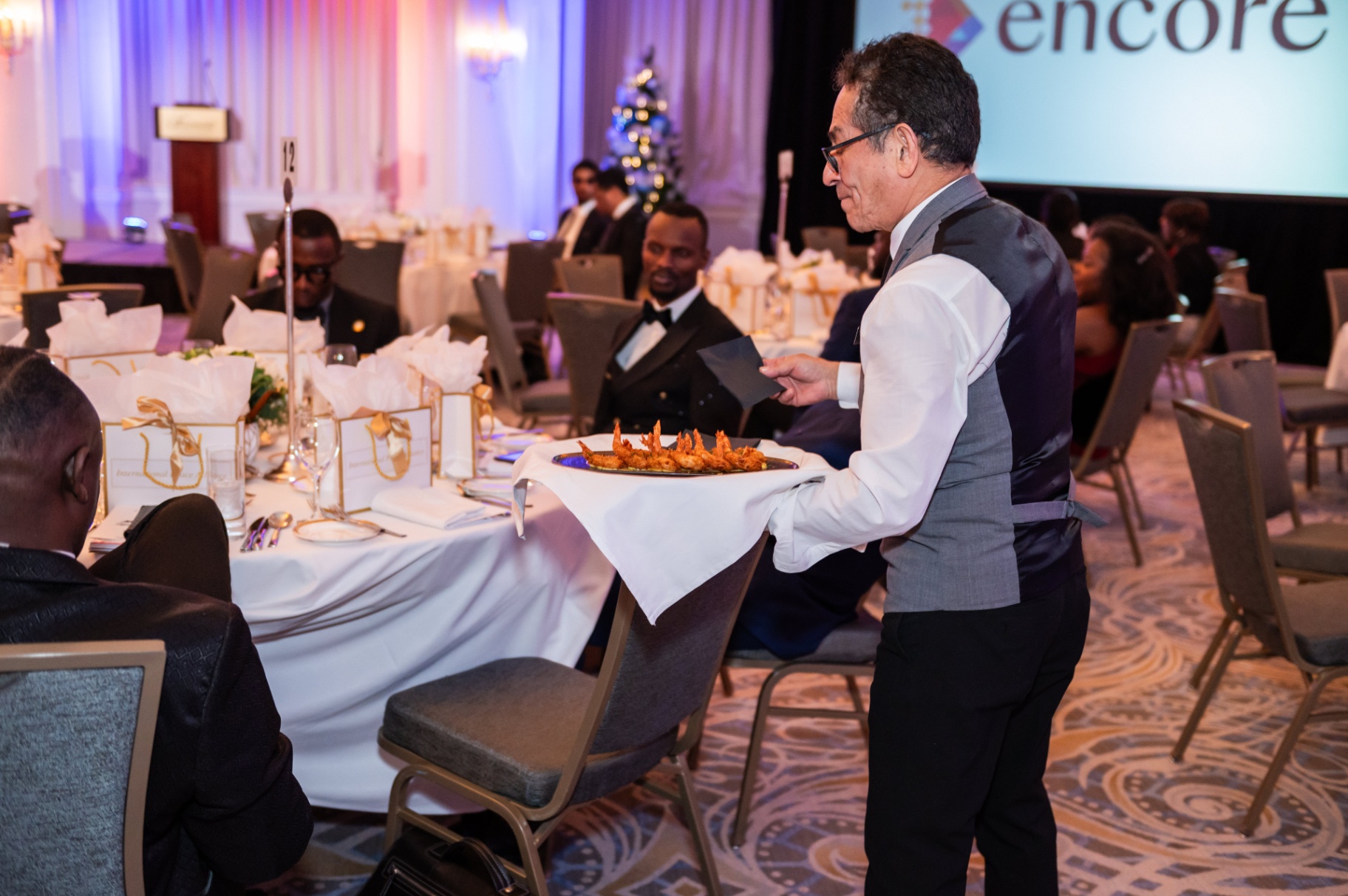Server presenting shrimp appetizers to guests during the gala dinner