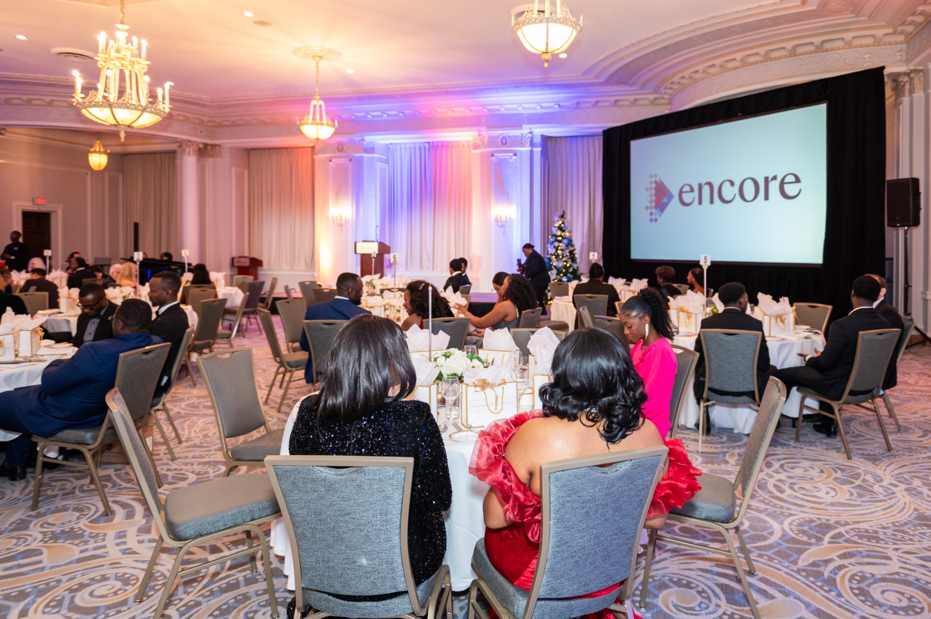 Ballroom view with the Encore stage screen and guests seated at round tables