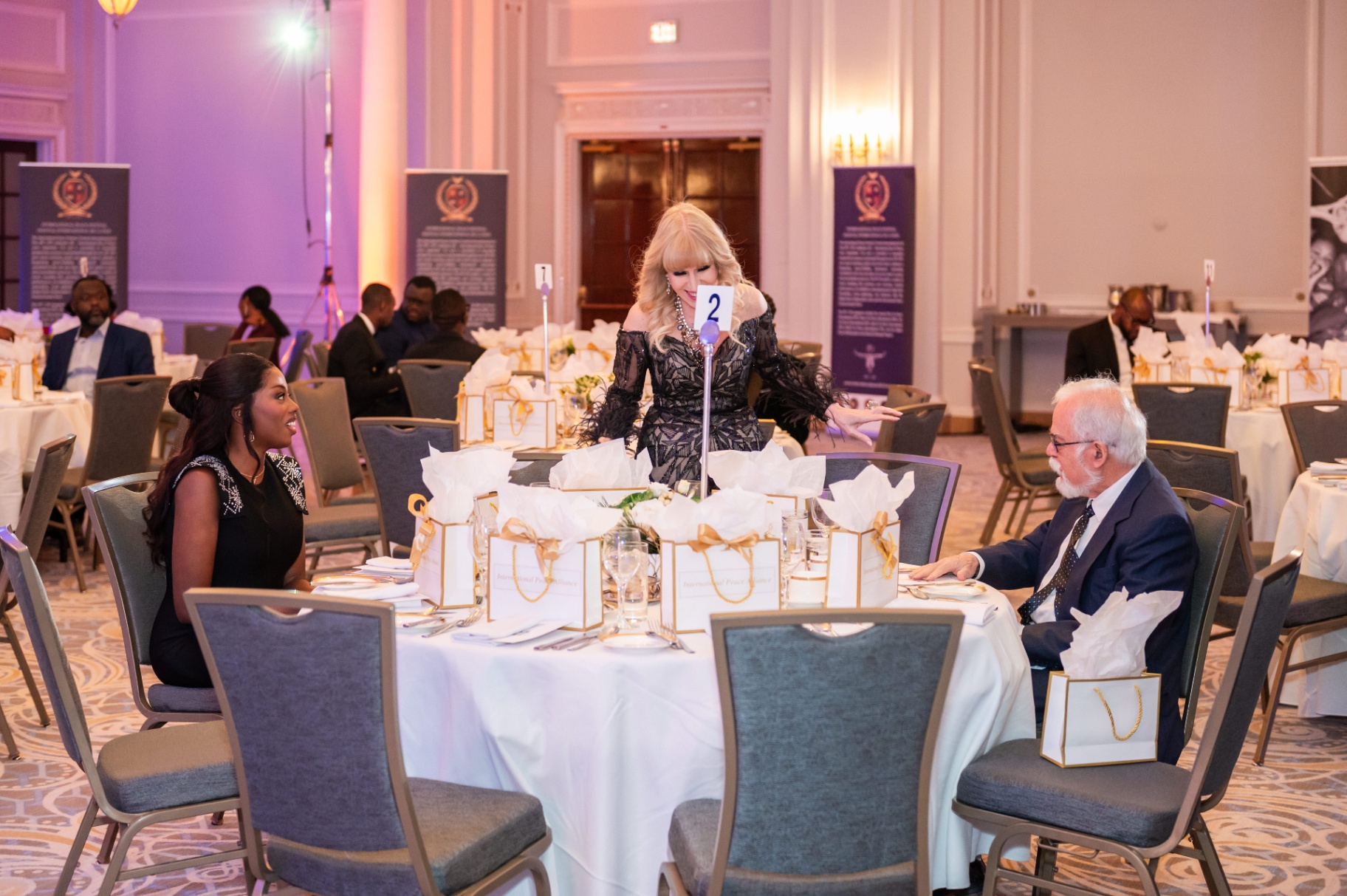 Host greeting attendees at the gala dinner table