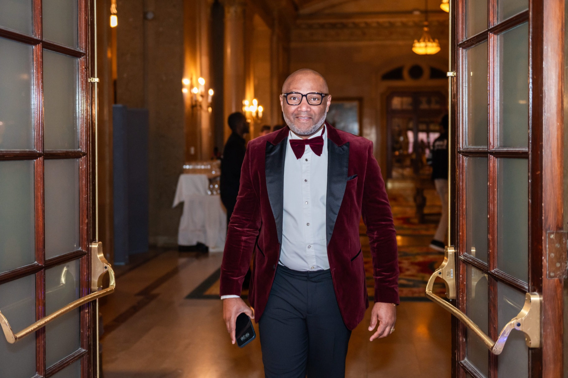 Portrait of the burgundy velvet tuxedo guest framed by the ballroom doorway