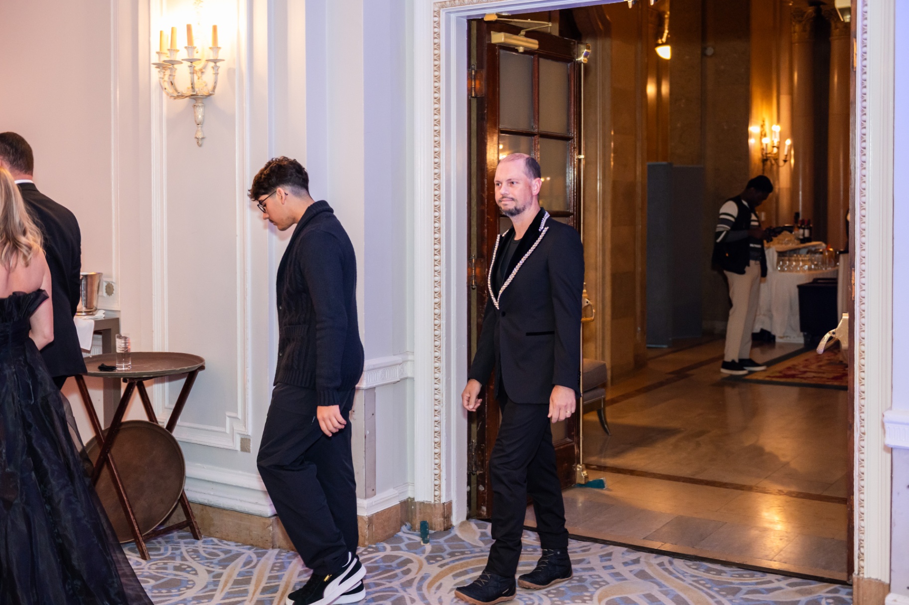 Guest in black embellished evening attire entering the gala foyer
