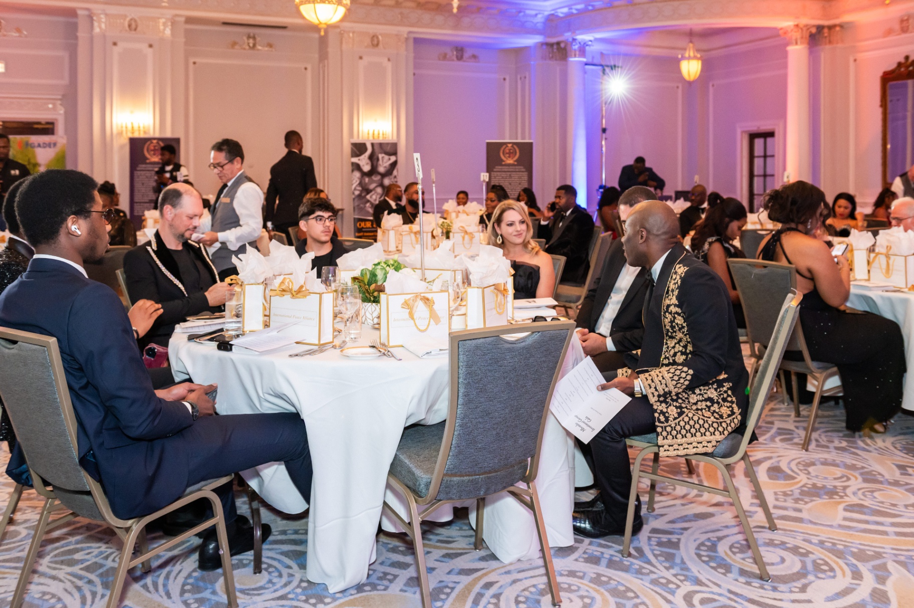 Wide ballroom view of guests seated at round tables during the gala program